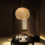 Plafonnier suspendu en bambou et en bois tissé à la main, avec lumière jaune, dans un salon de style chinois.