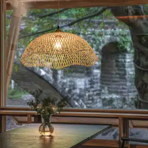 Plafonnier suspendu en bambou tissé à la main, design moderne, suspendu dans une pièce à vivre au-dessus d'une table.