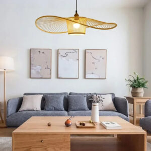Plafonnier naturel suspendu LED en rotin de style moderne dans une pièce sur fond gris avec une table en bois et un canapé avec des coussins et trois tableaux